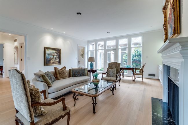 Living area featuring crown molding, a fireplace with flush hearth, light wood-style flooring, and recessed lighting | Image 5