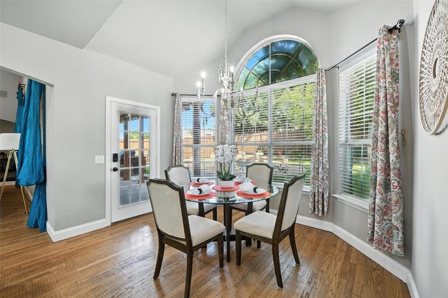 Dining area featuring a chandelier, vaulted ceiling, and wood finished floors | Image 11