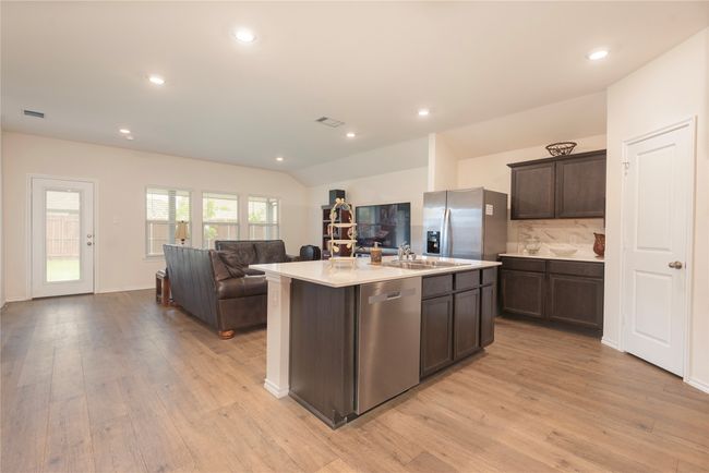 Kitchen featuring stainless steel appliances, light wood-type flooring, dark brown cabinetry, open floor plan, and recessed lighting | Image 24