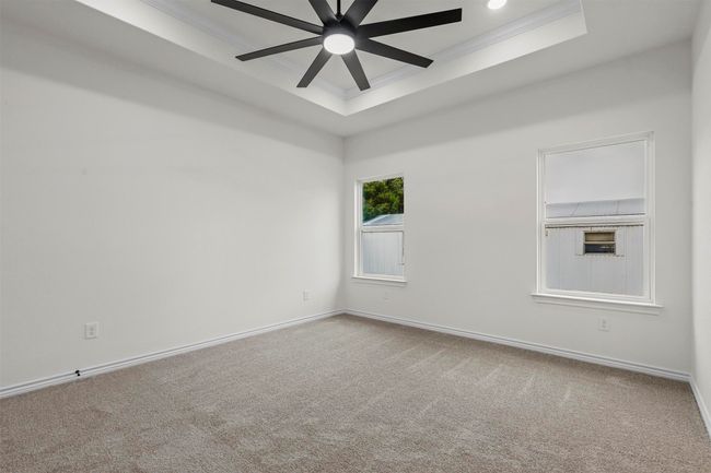 Carpeted empty room featuring ceiling fan, crown molding, and a raised ceiling | Image 24