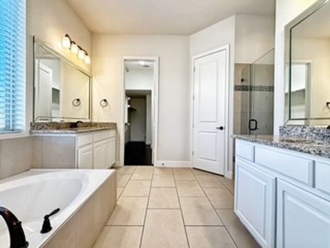 Bathroom featuring a shower stall, two vanities, a bath, and tile patterned floors | Image 12