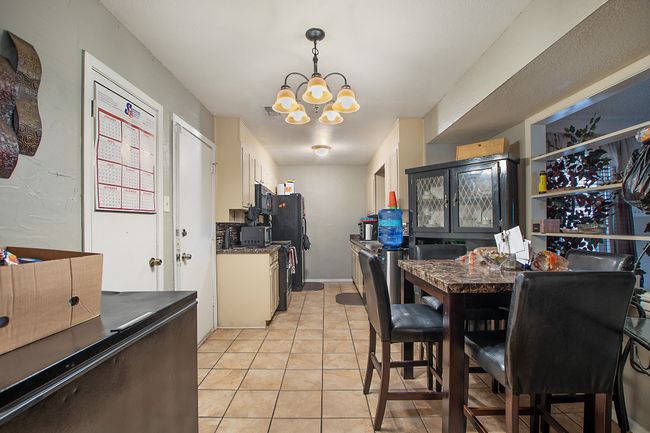 Dining room with light tile patterned floors and an inviting chandelier | Image 6
