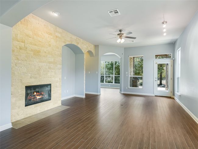 The living area features high ceiling, track lighting, wall niche for entertainment devices, gas powered fireplace and stone accent wall. | Image 9