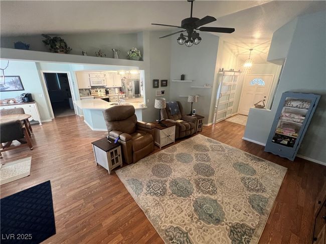 Living room featuring wood finished floors, a ceiling fan, a barn door, and high vaulted ceiling | Image 15