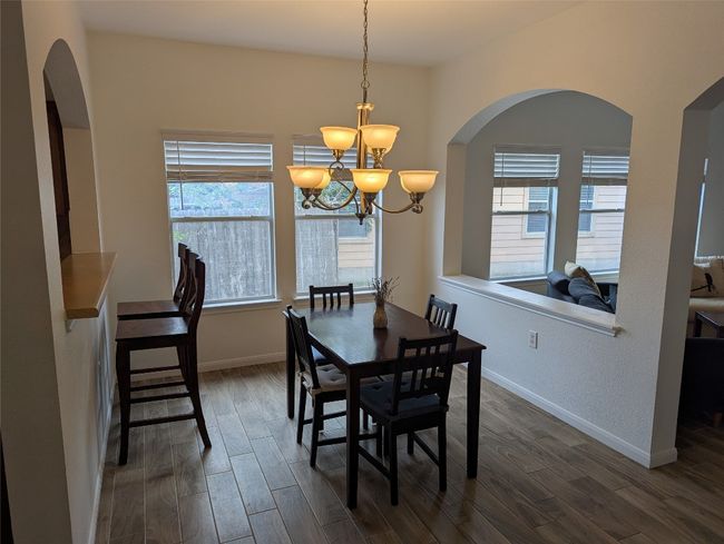 Dining room featuring a chandelier, dark wood finished floors, arched walkways, and baseboards | Image 7