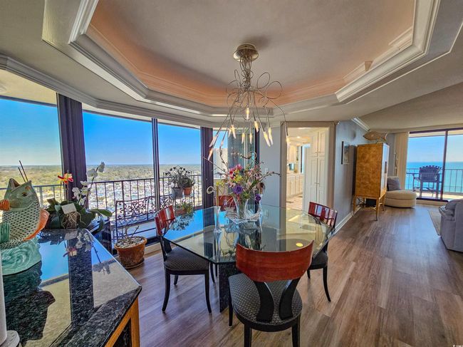 Dining room featuring crown molding, wood finished floors, floor to ceiling windows, a tray ceiling, and a notable chandelier | Image 16