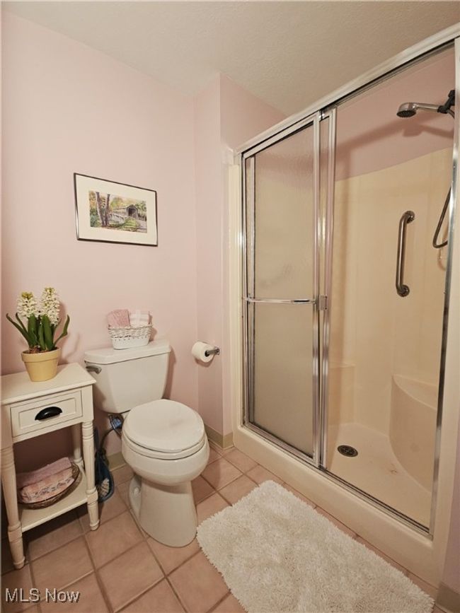 Bathroom featuring tile patterned floors, toilet, and a shower with shower door | Image 15