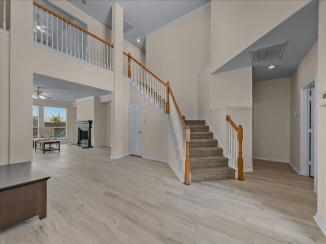Foyer featuring stairs, wood finished floors, a high ceiling, a fireplace with raised hearth, and a ceiling fan | Image 4