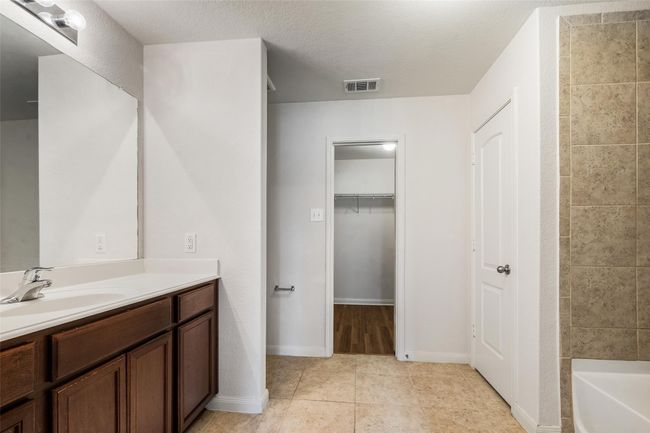 Full bathroom featuring vanity, tile patterned floors, a walk in closet, and baseboards | Image 13