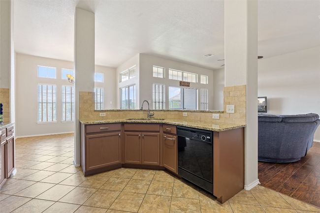 Kitchen featuring black dishwasher, decorative backsplash, a sink, and light tile patterned floors | Image 28