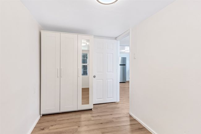 Unfurnished bedroom with freestanding refrigerator and light wood-type flooring | Image 33