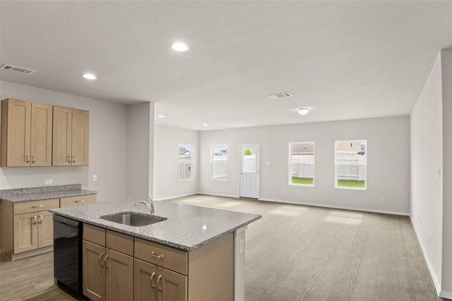 Kitchen with visible vents, dishwasher, a sink, an island with sink, and light stone counters | Image 6