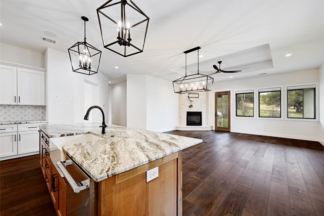 Kitchen with visible vents, dark wood-type flooring, a notable chandelier, light stone counters, and open floor plan | Image 14