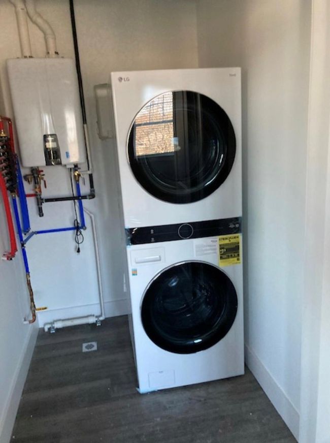 Laundry room featuring stacked washer / drying machine, water heater, baseboards, and dark wood finished floors | Image 5