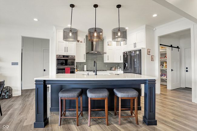 kitchen featuring white cabinets, tasteful backsplash, fridge with ice dispenser, light countertops, and double oven | Image 14