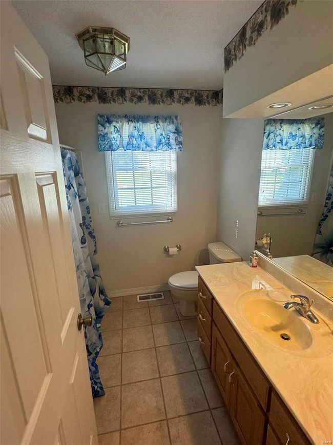 Bathroom featuring a healthy amount of sunlight, tile patterned floors, vanity, and toilet | Image 18