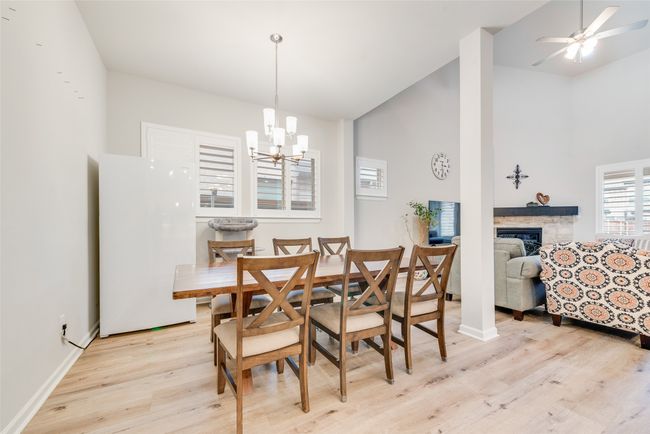 Dining room featuring a notable chandelier, baseboards, light wood finished floors, a fireplace, and high vaulted ceiling | Image 7