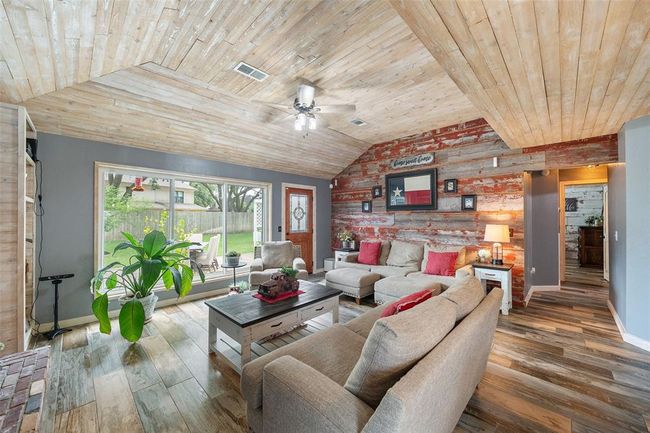 Large windows flood the space with natural light and offer a view of the lush, green backyard. The overall feel is warm, welcoming, and perfect for relaxing or entertaining. | Image 9
