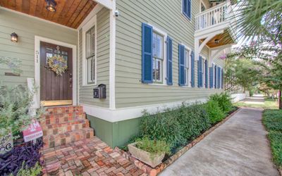 A brick-paved walkway leads you to the inviting entrance of this historic home. The solid wood door, complemented by a beadboard ceiling enhances the exceptional curb appeal and sets a warm, welcoming tone from the moment you arrive. | Image 3