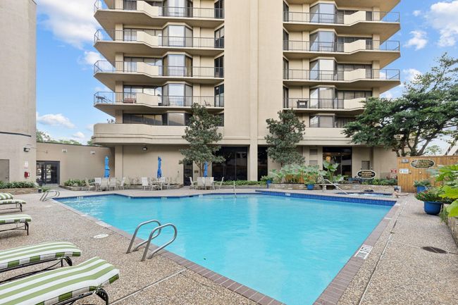 Spacious outdoor pool area complete with sun loungers and shaded seating, offering an inviting communal space for residents. | Image 31