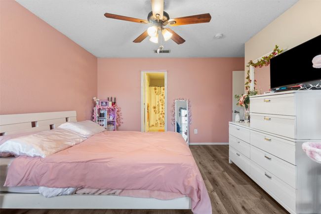 Bedroom with light wood-style floors, connected bathroom, baseboards, and ceiling fan | Image 18