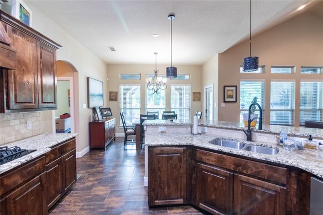 Kitchen featuring a sink, backsplash, light stone counters, and pendant lighting | Image 16