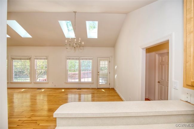 Living room featuring a chandelier, wood finished floors, a skylight, and high vaulted ceiling | Image 13