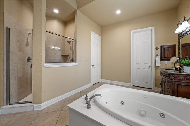 Bathroom with a whirlpool tub, vanity, a shower stall, tile patterned floors, and recessed lighting | Image 23