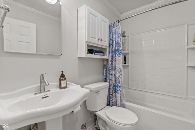 full bathroom featuring toilet, a sink, shower / bathtub combination with curtain, and crown molding | Image 25