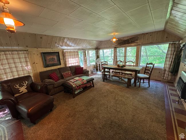 Living room featuring lofted ceiling, wood walls, and carpet flooring | Image 4