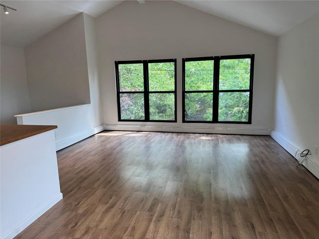 Living room, dining room plenty of lolnatural light, lofted ceiling, wood finished floors, and baseboards | Image 5