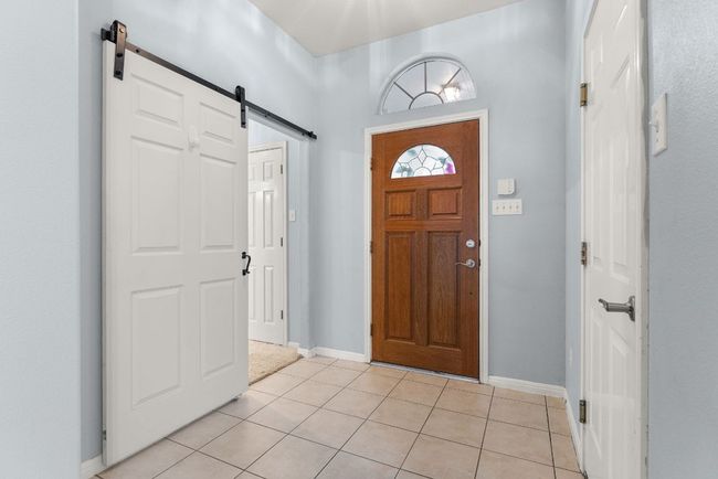 Entrance foyer featuring baseboards, a barn door, and light tile patterned floors | Image 5