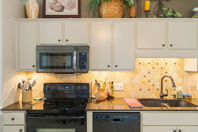 Kitchen featuring a sink, black appliances, and white cabinetry | Image 12