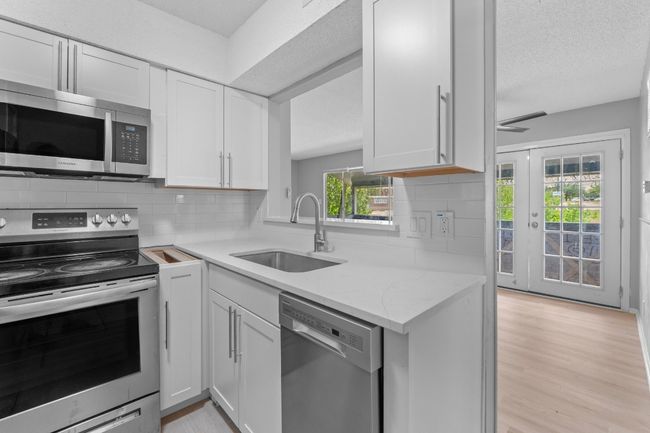 Kitchen with white cabinets, appliances with stainless steel finishes, decorative backsplash, and a sink | Image 12