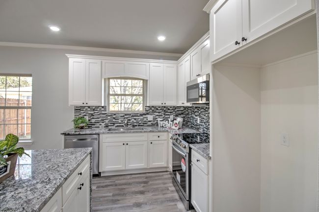 Kitchen with appliances with stainless steel finishes, crown molding, light wood-type flooring, white cabinetry, and tasteful backsplash | Image 8