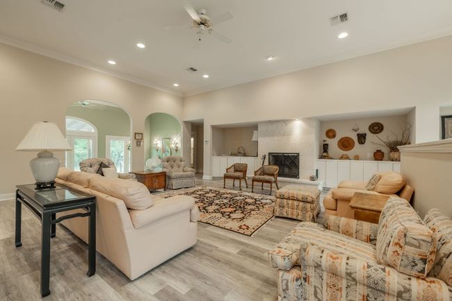 Living area featuring a ceiling fan, crown molding, recessed lighting, light wood-style flooring, and a fireplace with raised hearth | Image 7