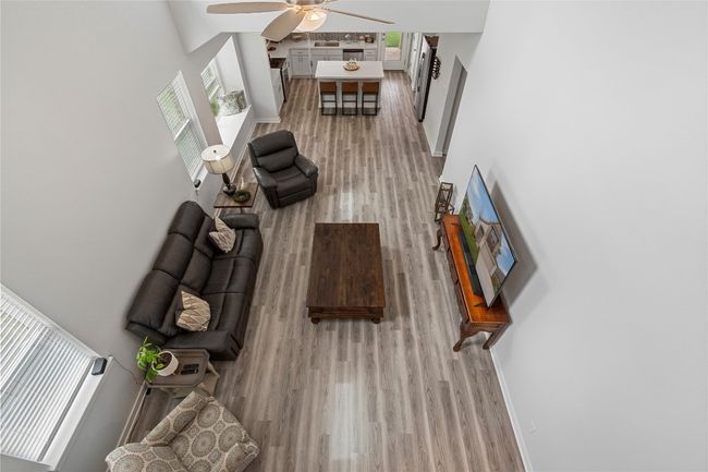 Living room featuring wood finished floors, ceiling fan, a high ceiling, and baseboards | Image 32