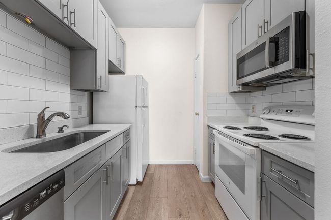 Kitchen with appliances with stainless steel finishes, a sink, decorative backsplash, and light wood finished floors | Image 6