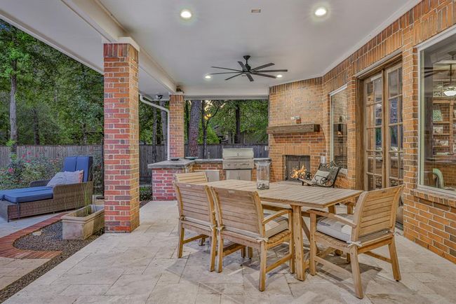 Step outside to a beautifully designed covered patio, perfect for year-round enjoyment. This inviting space features recessed lighting and an updated ceiling fan to keep you comfortable no matter the season. The outdoor kitchen is equipped with a built-in grill, beverage refrigerator and sink, making it ideal for alfresco dining and entertaining. A charming corner fireplace adds warmth and ambiance, creating the perfect spot to unwind on cool evening with family and friends. | Image 43
