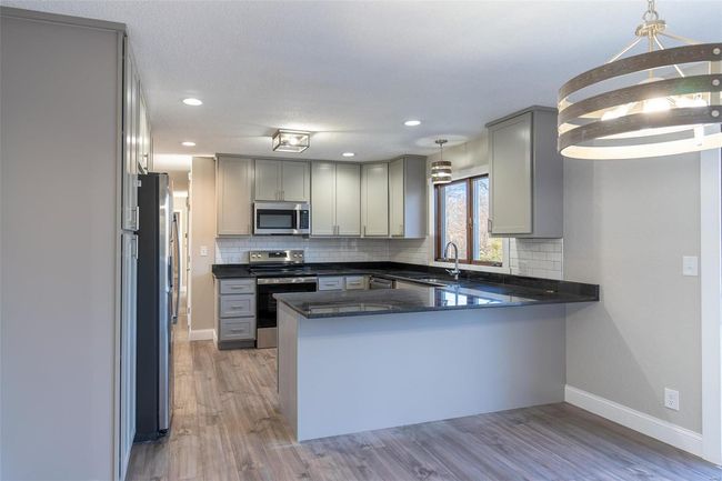 Kitchen with wood-style floors, decorative light fixtures, kitchen peninsula, and stainless steel appliances | Image 35