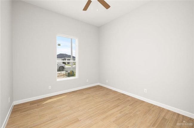 Empty room with light wood-style floors, baseboards, and a ceiling fan | Image 12