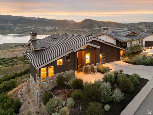 View of front facade featuring a standing seam roof, stone siding, a chimney, a metal roof, and a mountain view | Image 8