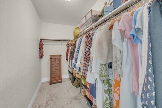 Walk in primary closet featuring marble finish floor | Image 22