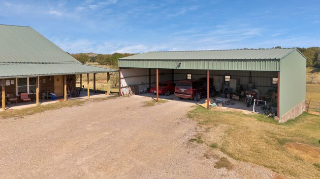 View of pole building with a detached carport and dirt driveway | Image 7