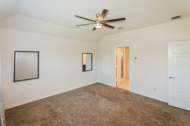 Carpeted empty room featuring lofted ceiling, a ceiling fan, and baseboards | Image 19