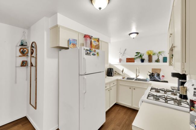 Kitchen featuring white appliances, dark wood-style flooring, light countertops, and open shelves | Image 6