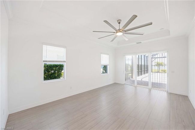 Empty room with a wealth of natural light, a ceiling fan, baseboards, and a raised ceiling | Image 14
