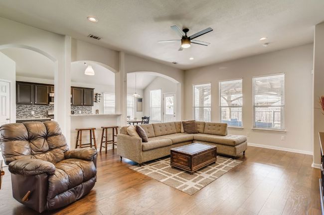Living area with arched walkways, a ceiling fan, recessed lighting, wood finished floors, and vaulted ceiling | Image 14
