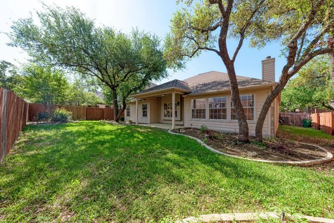 Back of property with a chimney, a fenced backyard, a patio area, and a lawn | Image 34