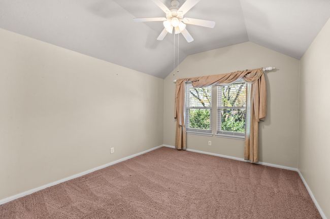 Empty room with light carpet, vaulted ceiling, and a ceiling fan | Image 18
